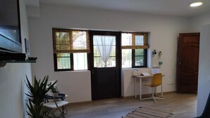 Ein Zimmer mit Schreibtisch, Stuhl, Topfpflanze und einer Tür.