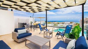 Terraço no telhado com área de estar externa, piscina e vista da cidade.
