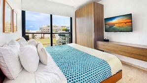 Quarto de hotel moderno com uma cama grande, uma televisão e uma varanda com vista para a cidade.