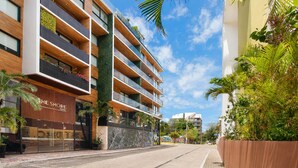 Um hotel com vários andares, varandas, um jardim vertical e um céu azul límpido.