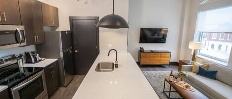 Una cocina moderna con una isla grande, electrodomésticos de acero inoxidable y un comedor con banco y mesa.