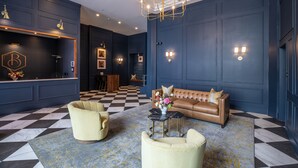 A modern lobby with a checkered floor, a leather sofa, and a chandelier.