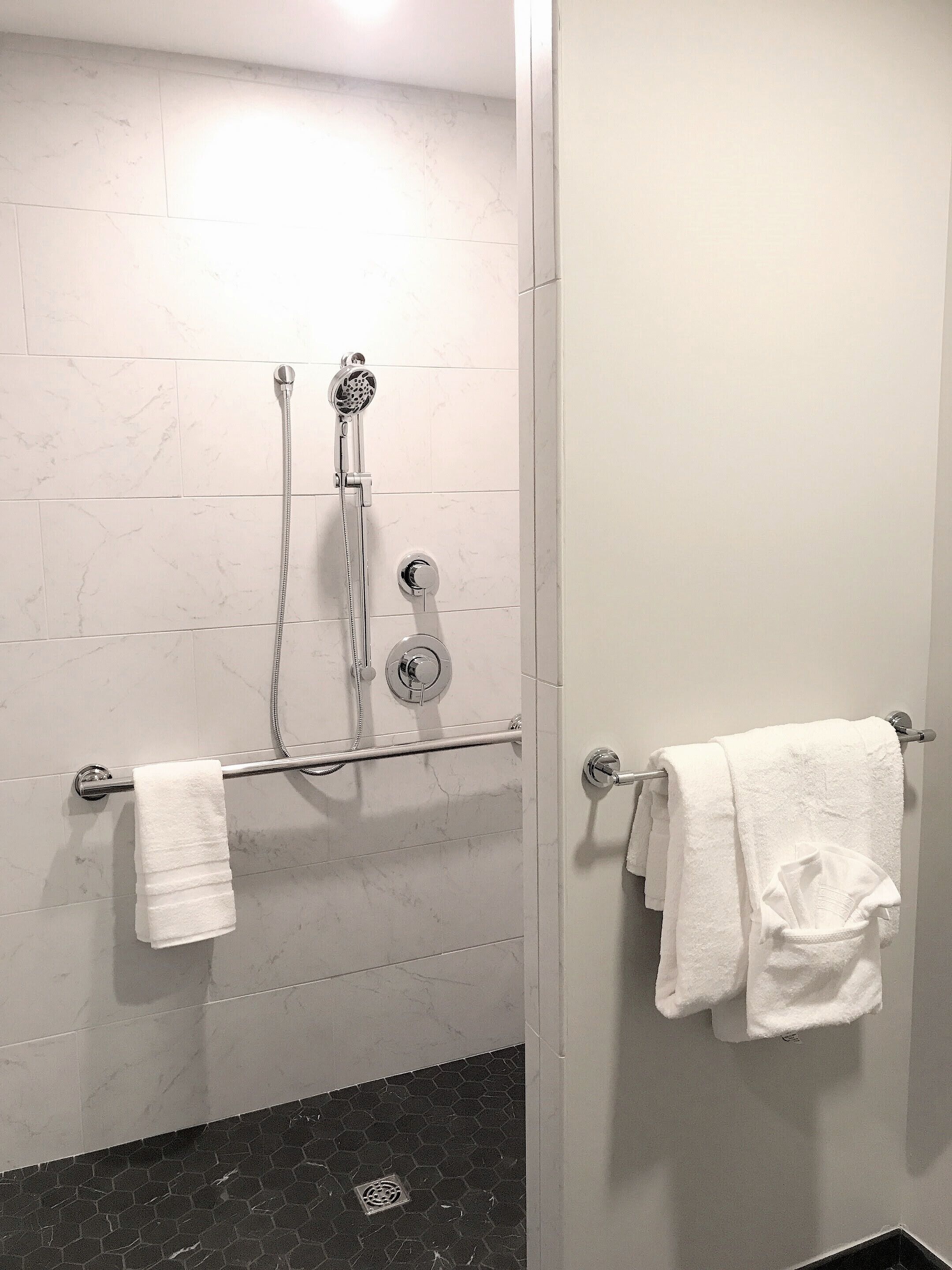Un baño con ducha, toallero y piso de baldosas.