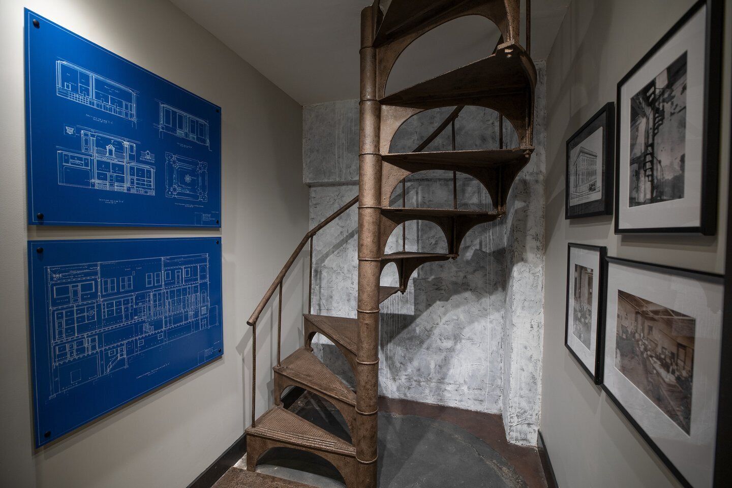 Eine Wendeltreppe mit blauen Architektenplänen an der Wand.