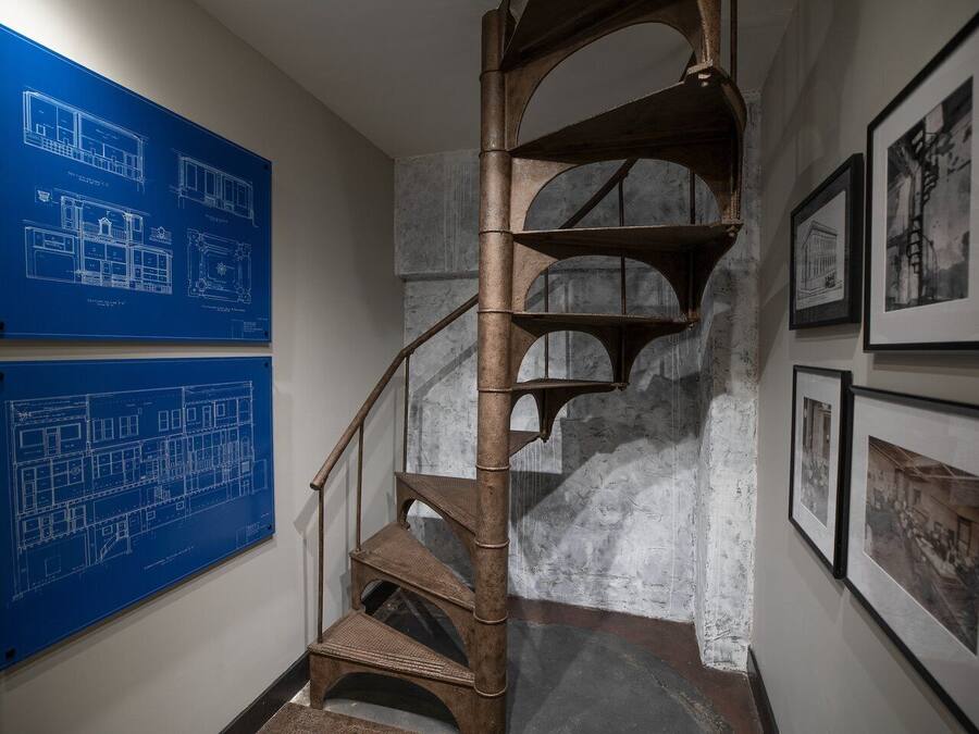 Una escalera en espiral con planos arquitectónicos azules en la pared.