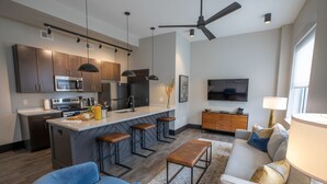 A modern kitchen with a central island, bar stools, and a dining area.