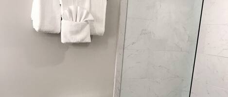 A modern bathroom with a toilet, a glass shower enclosure, and a towel rack.