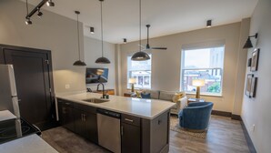 A modern kitchen with a large island, dark cabinetry, and pendant lighting.