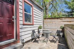 A patio with a red door, a window, and a small table with chairs.