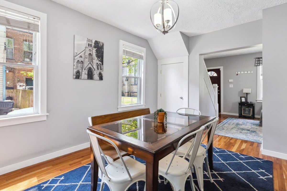 A dining area with a glass-top table, white chairs, and a chandelier.