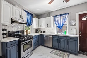 A kitchen with white cabinets, a stove, and blue curtains.