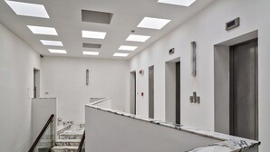 Een moderne hotelgang met een marmeren trap, inbouwspots en deuren van de lift.