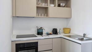 A compact kitchen with a dishwasher, a sink, and a small countertop. There are cabinets above the countertop, and a basket is visible on the countertop. - Deluxe Apartment - Ice by Wonderful Italy (Genova)
