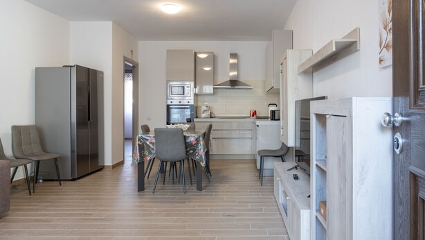 Une cuisine moderne équipée d’un réfrigérateur, d’un four à micro-ondes, d’un four et d’un évier. Un coin repas avec une table et des chaises est également à disposition.