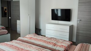 Une chambre à coucher avec un lit, un téléviseur fixé au mur, une armoire et un miroir.