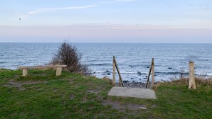 Un sentier côtier avec un banc en bois et un panneau indiquant un point de vue.