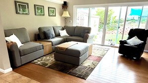 A living room with a sectional sofa, a coffee table, and a chair. There is a sliding glass door leading to a patio. - Spectacular Ocean View! (Rancho Palos Verdes)