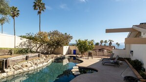 A swimming pool with a stone-lined edge, lounge chairs, and palm trees in a resort setting. - Spectacular Ocean View! (Rancho Palos Verdes)