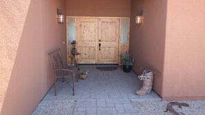 A wooden door with two glass panels, a bench, a potted plant, and a pair of boots leaning against the wall. - 5yr old home , private, 1-BdRm home on its own 3.3 acres with city views (Tucson)