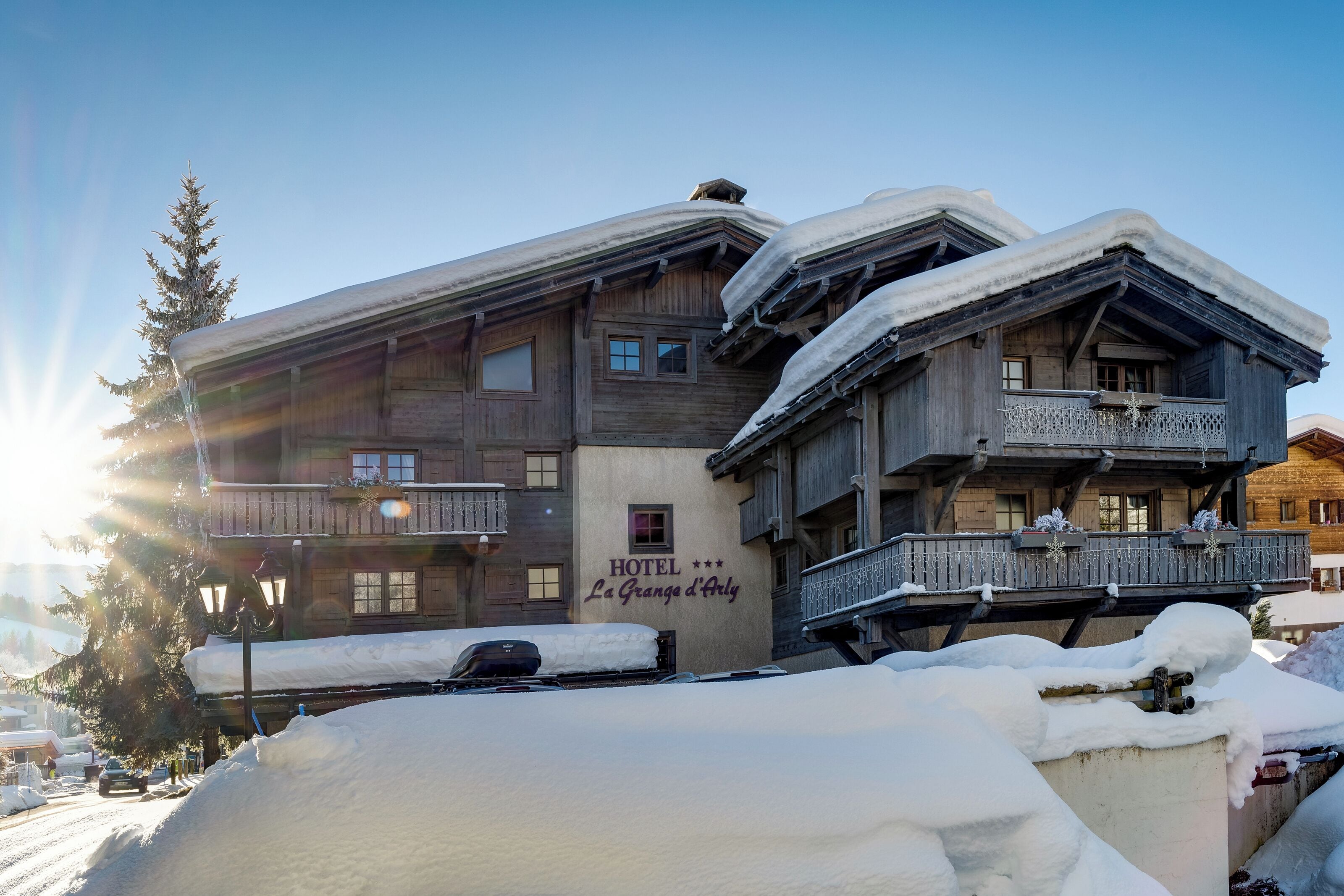 Un hôtel en bois, doté de balcons, sur lequel on peut lire l’inscription « HÔTEL La Grande d’Arly ».