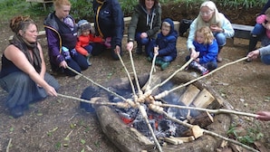 En grupp människor samlade runt en lägereld i en naturskön miljö.