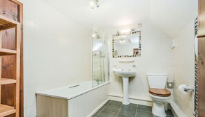 A bathroom with a shower, sink, toilet, and wooden shelving.