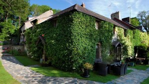 Una casa cubierta de hiedra, con un camino de piedra que lleva a un patio.