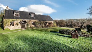 A stone house with a sloped roof, a front door, and a small porch.
