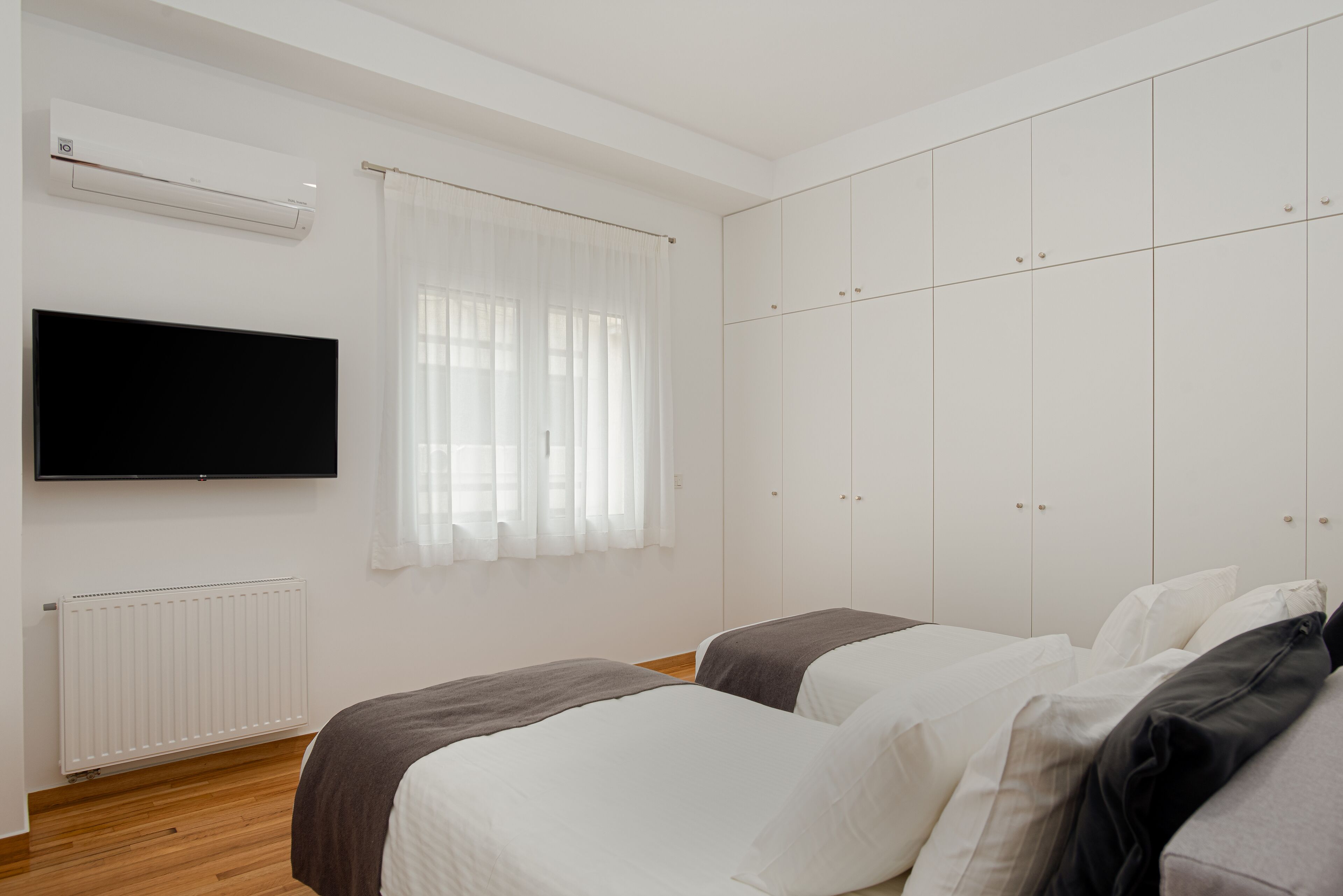 Une chambre avec deux lits, une télévision, un radiateur et une armoire.