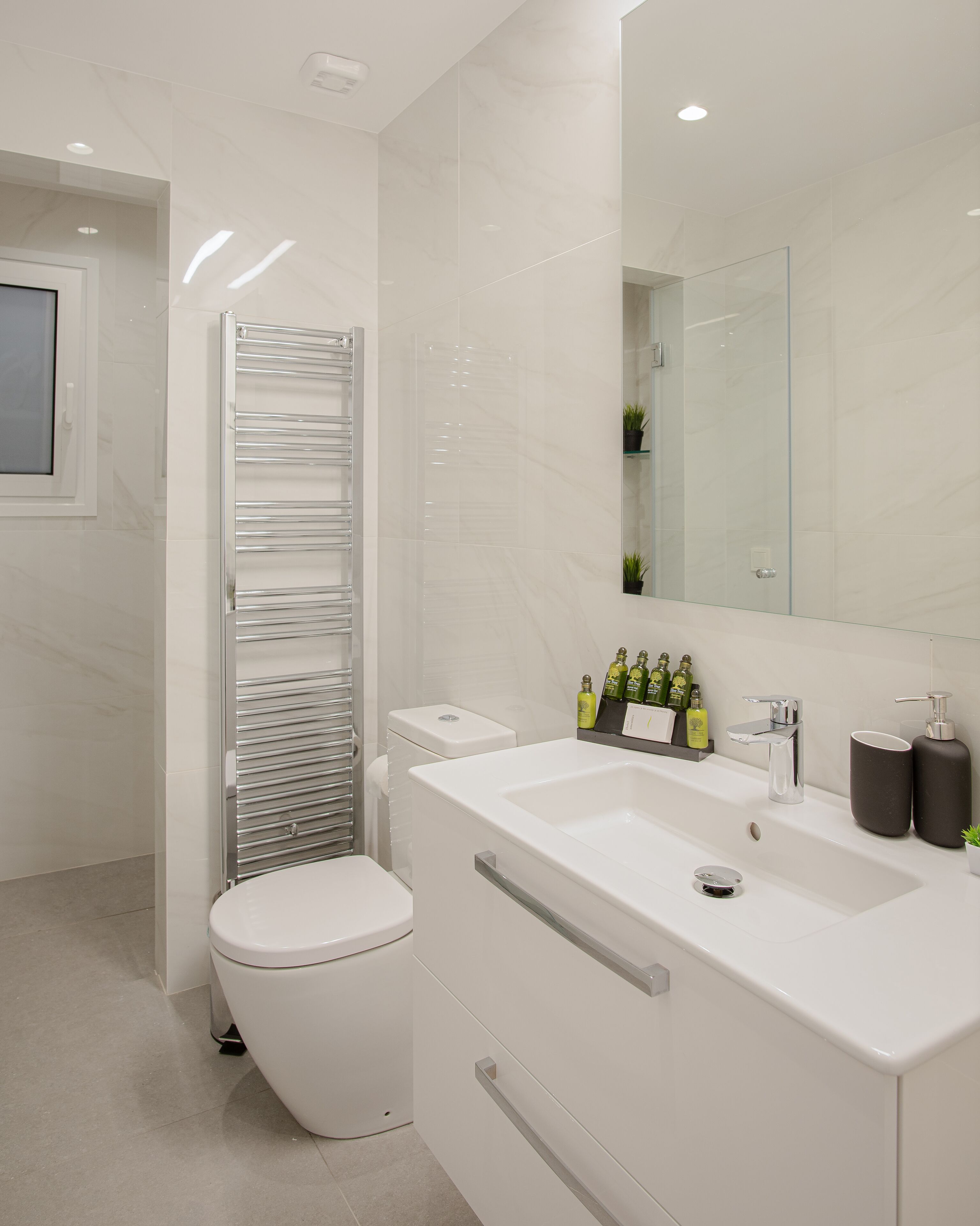 Un baño moderno con inodoro blanco, cabina de ducha de vidrio y tocador con lavabo y espejo.