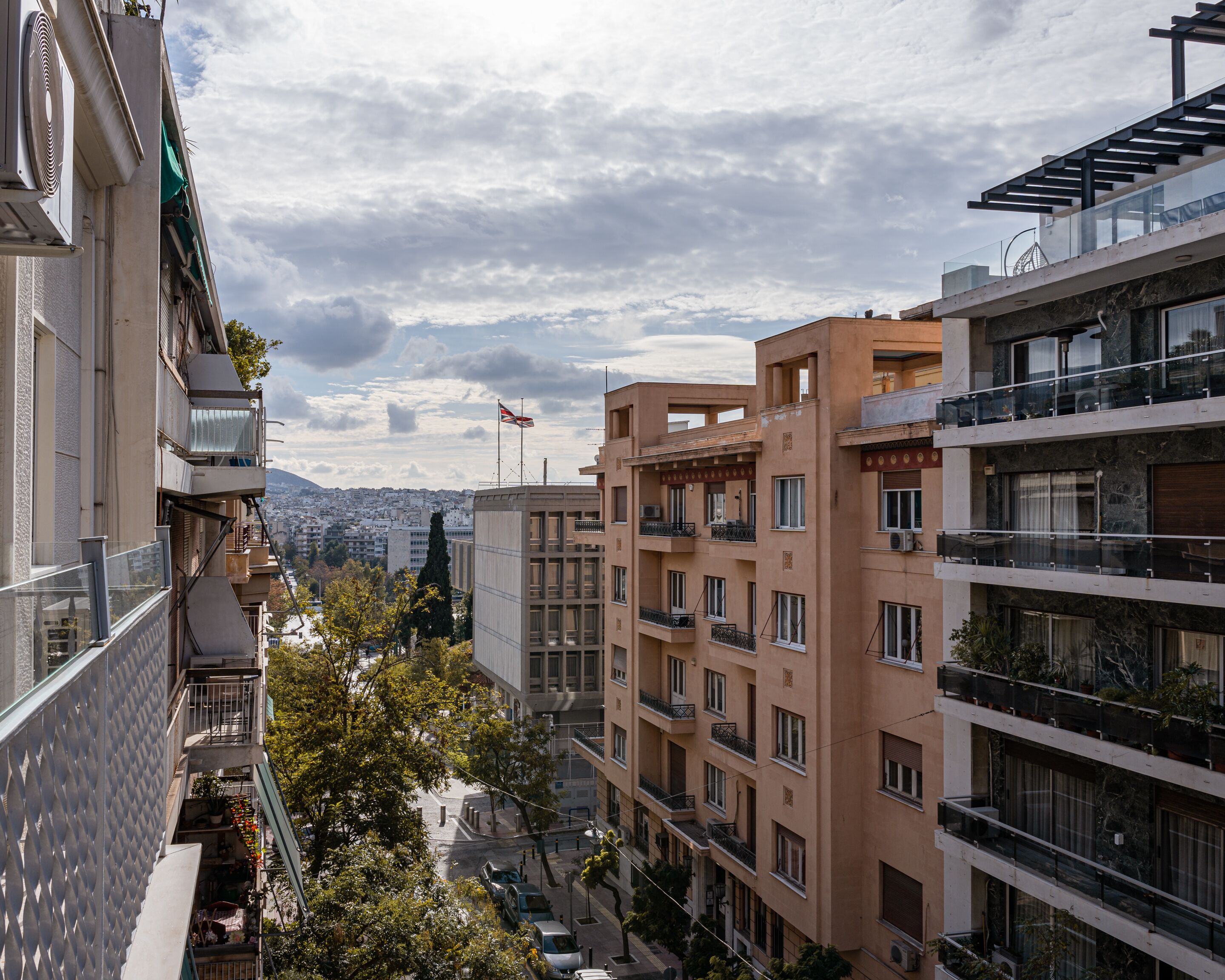 A multi-story residential building with balconies, a clear view of the cityscape, and a flag on top.