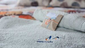 A neatly folded towel with a tag, placed on a bed with a patterned bedspread. - Two-level marvel in exotic fruit orchard (Ribeira Grande)
