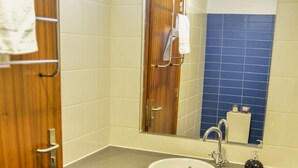 Un baño con tocador de madera, lavamanos y espejo.