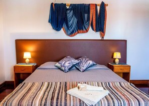 A neatly made bed with a striped bedspread, two bedside lamps, and a headboard.