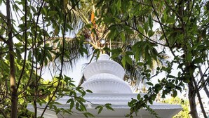 A white gazebo with intricate carvings, surrounded by lush greenery and a body of water in the background. - Geeta Bhawan (Karjat)