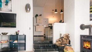 A modern living room with a fireplace, a TV, and a kitchen in the background. - 4 Star Holiday Home in Blavand (Blavand)