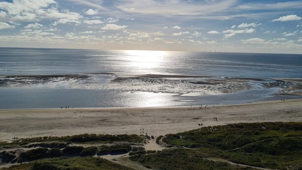 A coastal landscape with a beach, a path leading to the water, and a distant view of wind turbines. - 4 Star Holiday Home in Blavand (Blavand)