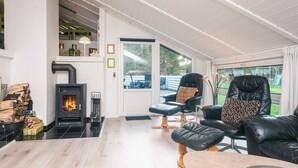 A modern living room with a fireplace, leather furniture, and a view of the outdoors. - 4 Star Holiday Home in Blavand (Blavand)