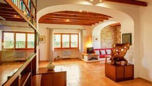 A spacious living room with a wooden ceiling, a red sofa, a stone wall, and a large wooden sculpture. - rose village (Sant Josep de sa Talaia)