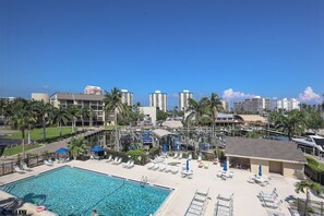 Ein Hotelpoolbereich mit Liegestühlen, einem Schwimmbecken und Blick auf hohe Gebäude im Hintergrund.