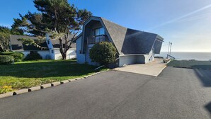 A modern house with a sloped roof, a front porch, and a view of the ocean.