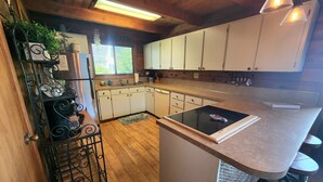 A kitchen with white cabinets, a black countertop, and a small island with stools.