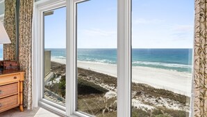 Ein Zimmer mit großem Fenster und Blick auf Strand und Meer.