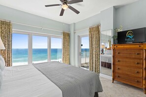 Ein Schlafzimmer mit einem Bett, einem Deckenventilator, einem Fernseher und Blick auf den Ozean.