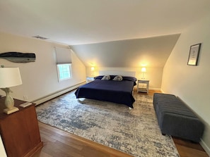 A bedroom with a bed, bedside lamps, a bench, a window, and a wall-mounted shelf. - Pet friendly and spacious home in quiet neighborhood! (Chatham)