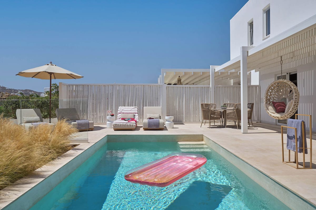 Un espace piscine équipé d’un tapis flottant, de chaises longues et d’un fauteuil suspendu.