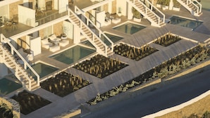 A modern multi-level residential building with multiple swimming pools, outdoor seating areas, and a rooftop garden.