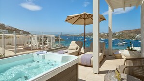 A rooftop terrace with a hot tub, lounge chairs, and a view of the sea.