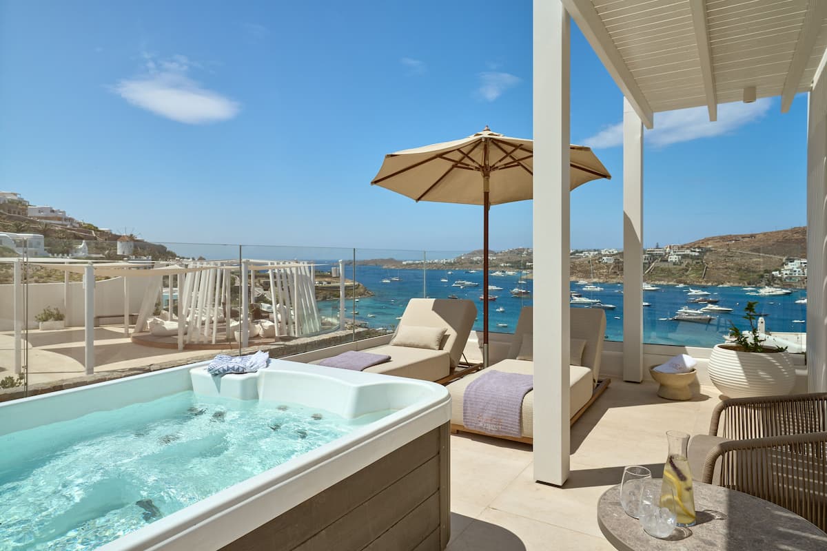 Une terrasse sur le toit avec un jacuzzi, des chaises longues et une vue sur la mer.