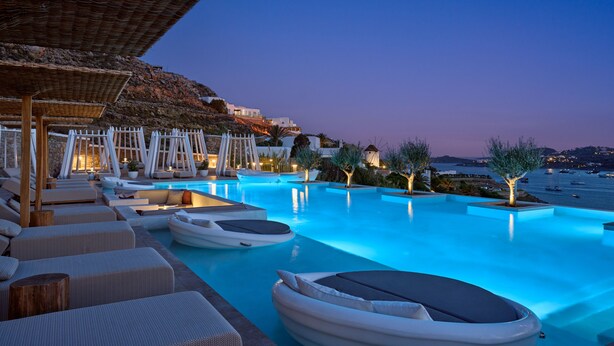 A poolside area with lounge chairs, umbrellas, and boats.